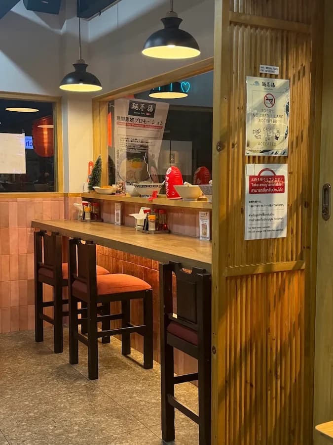麺屋 福の店内。木のカウンター席に赤い座面の椅子が並び、笠付きのペンダントライトが灯っている